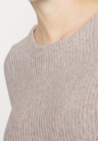 Rippstrick-Langarmshirt in hellem Beige, mit Rundhalsausschnitt und weicher Textur, horizontalen Streifen und figurbetonter Passform.