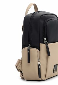 Czarny i beżowy plecak z gładkiego materiału syntetycznego, z dwiema zapinanymi na zamek komorami oraz kontrastującymi suwakami. Wyposażony w górny uchwyt oraz regulowany pasek.