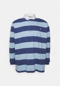 Långärmad polo-tröja i växlande ljusblå och marinblå ränder. Har en vit krage och en liten broderad logotyp på bröstet.