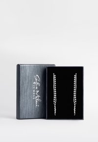 Sölvfärgade rhinestone-örhängen som visas i en svart sammetfodrad låda. Varje örhänge har en linjär design med flera facetterade stenar.