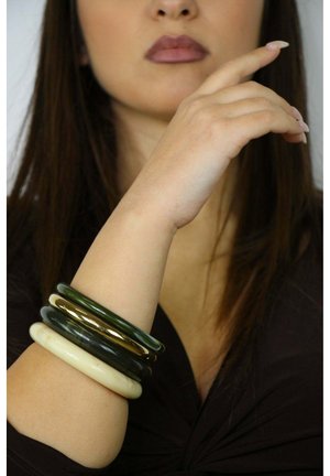 Vier armbanden in verschillende materialen: groen, goud, donkergroen en crèmekleurig. Ze hebben gladde oppervlakken en een ronde, gestapelde vorm.