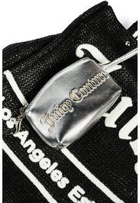 Svart texturerad tote-väska med vit text, försedd med en metallisk silverficka med "Juicy Couture" präglat i guld.