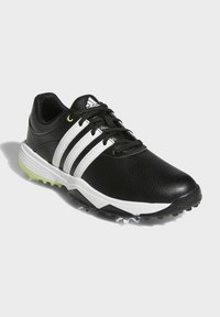 Czarne skórzane buty golfowe z trzema białymi pasami, teksturowana powierzchnia, czarne sznurowadła oraz podeszwa z zielonym akcentem z wyprofilowanymi kolcami.