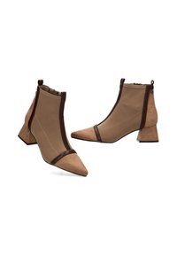 Botas de tobillo marrones con punta afilada, de ante y material suave, con un ribete marrón en contraste y un tacón grueso y rectangular.