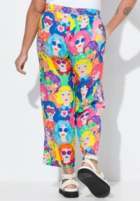 Barevné široké kalhoty s vzorem ilustrovaných tváří s různými účesy a slunečními brýlemi. Materiál vypadá lehce a živě.