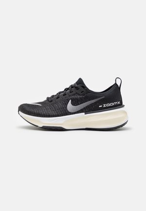 Black Nike running shoe with knit upper, white Swoosh logo, lightweight design, and ZoomX cushioning in the sole. Patterned mesh texture.