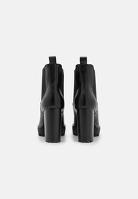 Mustat nilkkurit, joissa on sileä synteettinen päällinen, korkeat lohkareet ja vetotapit. Varustettu elastisilla sivupaneeleilla ja teksturoiduilla pohjilla.