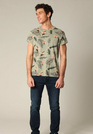 T-shirt à manches courtes de couleur olive avec un motif floral comportant des fleurs roses et des feuilles vertes, complété par une poche sur la poitrine et un col rond.