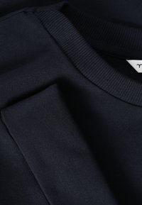 Sweat-shirt en coton bleu marine foncé avec col rond côtelé et manches repliées.