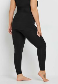 Svarta leggings i stretchigt tyg, figurnära design, slät yta och ankellängd utan synliga mönster eller dekorationer.