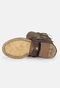 Hnědé kožené kotníkové boty s přezkami, texturovaným svrškem a gumovou podrážkou s plochým designem a mírným zakřivením na špičce.