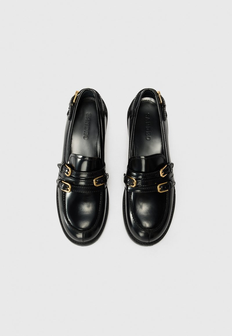 Zwarte leren schoenen met een ronde neus, voorzien van twee gouden gespen en een zijrits. Gladde textuur met stiksels accentuering.