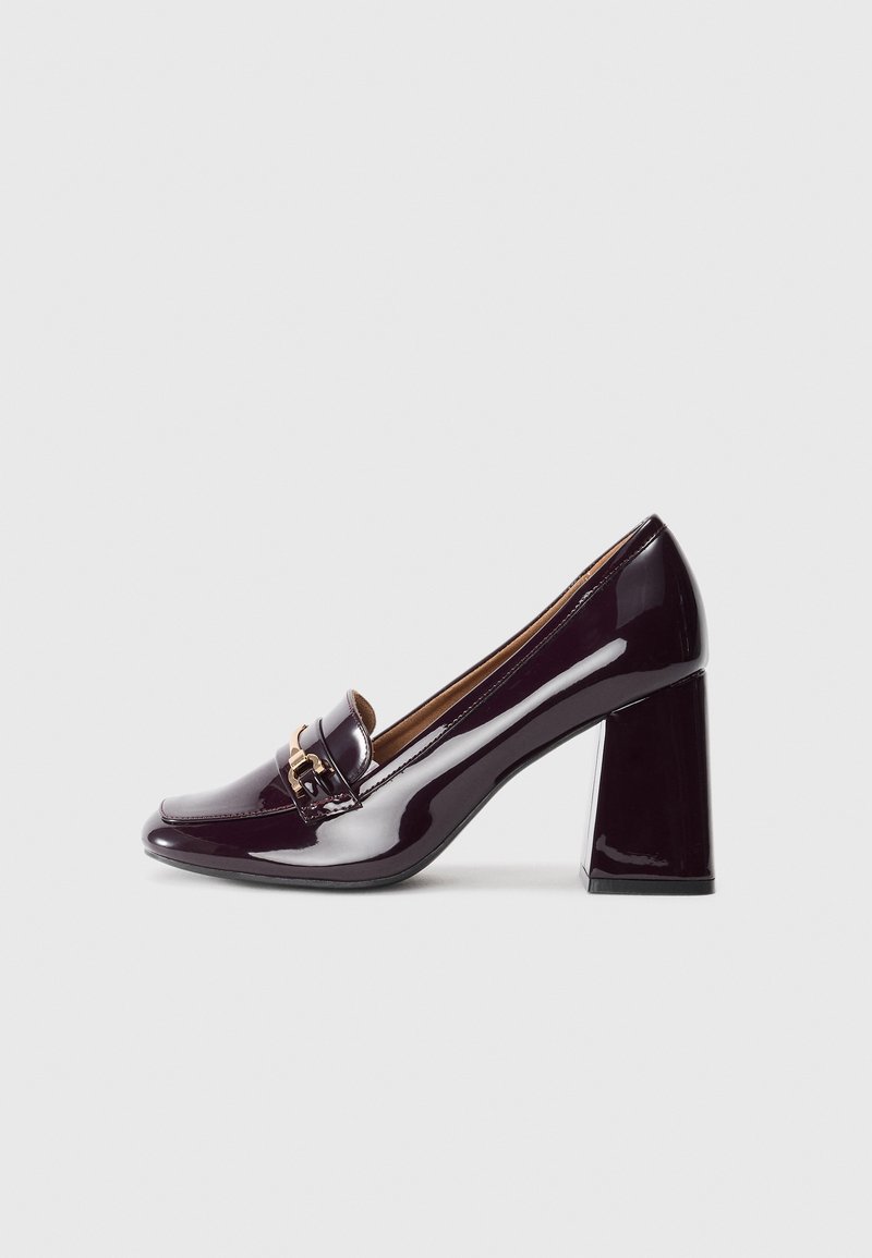 High-heeled loafers in glossy deep purple patent leather, featuring a rounded toe and a gold-tone buckle detail on the upper.