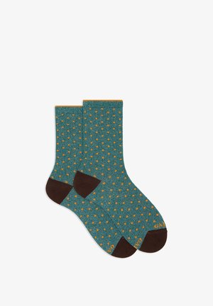 Calze lavorate a maglia in verde acqua con un motivo a pois arancioni su tutta la superficie, con tacco e punta marroni e polsini a coste arancioni.