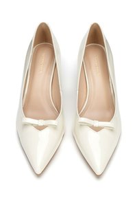 Décolleté in pelle verniciata bianca con punta affusolata e piccolo fiocco decorativo sul davanti, con interno color nude e silhouette elegante.