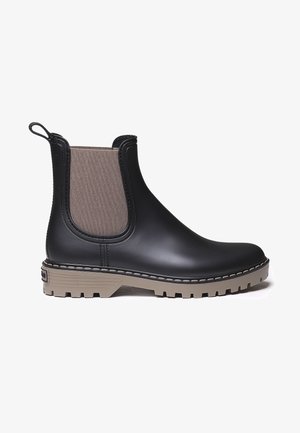 Black rubber ankle boots with a tan elastic panel, textured sole, and a pull tab. The design features a chunky, treaded outsole.