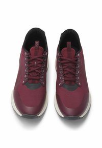 Maroon athletic shoes with a textured upper, black accents, laces, and a white sole. Features a smooth toe cap and reinforced heel area.