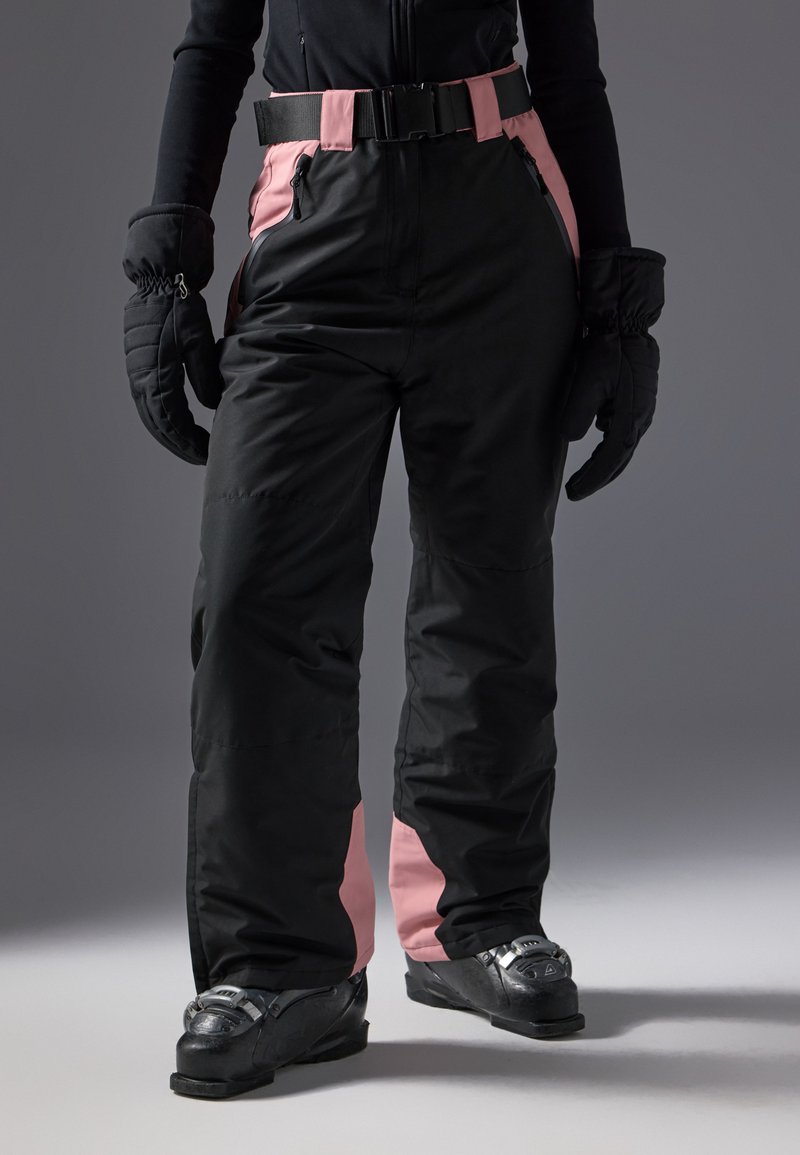 Black snow pants with pink side panels, equipped with a black belt, and worn with black ski boots. The fabric appears water-resistant.