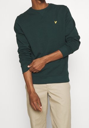 Sudadera de cuello redondo de color verde oscuro, hecha de algodón, con puños y dobladillo acanalados, y un pequeño logotipo amarillo en el lado izquierdo del pecho.