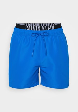 Blå svømmedrakter med elastisk midjebånd, med svart og hvit merkevarelogo detaljer, justerbar snor og en glatt tekstur.