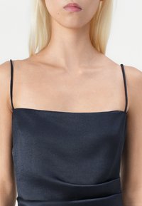 Μπλε σατέν φόρεμα με λεπτές τιράντες, τετράγωνη λαιμόκοψη και ομαλό, υφασματοποιημένο ύφασμα με ραμμένες λεπτομέρειες στη μέση.