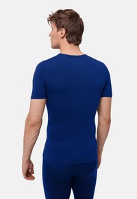 Royalblå kortærmet skjorte med rund halsudskæring, figursyet design og glat tekstur. Har en sømløs ryg og pæn syning.