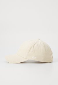 Cream corduroy baseball cap with a curved brim, embroidered detail on the front, and ventilation eyelets on the sides.