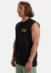 Black sleeveless cotton shirt featuring a colorful embroidered logo on the chest, with a relaxed fit and a smooth texture.