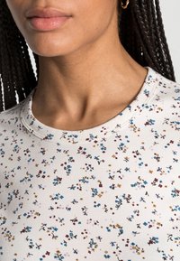 Lichtgekleurde bloemen-t-shirt met een ronde hals, verspreide meerkleurige bloemen en een zachte, gladde textuur.