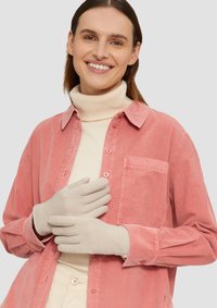 Beige handschoenen met een ontwerp met vijf vingers, weergegeven tegen een lichtroze corduroy shirt en een roomkleurige coltrui, die textuur en neutrale kleuren benadrukken.