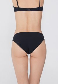 Černé bikiny s hladkým povrchem, vysokým vykrojením na nohavicích a bezšvým provedením, navržené pro pohodlí a zakrytí.