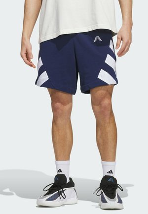 Male wearing navy blue athletic shorts with white diagonal stripes, white crew socks, and black and white sneakers standing on a plain background.