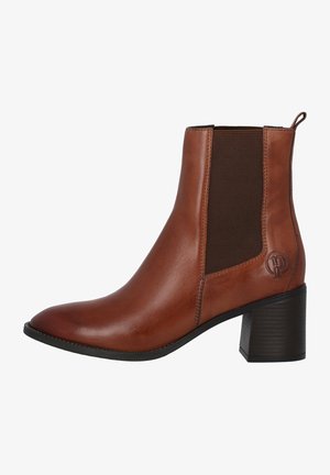 Bottine en cuir marron avec panneau latéral élastique, talon bloc et une languette à l'arrière, affichant un petit logo embossé près du talon.