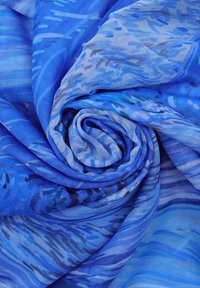 Tessuto a fantasia blu, leggero e testurizzato, con disegni vorticosi in diverse sfumature di blu e punte di viola e verde.