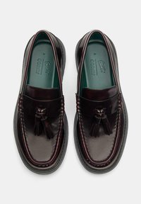 Bordeaux leren loafers met kwastaccenten, ronde vorm, gestikte details en stevige zwarte rubberen zolen. Groene binnenzool zichtbaar.