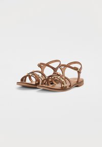 Bruna lädersandaler med flera smala remmar, guldfärgade detaljer, en platt sula och en öppen design med en perforerad fotbädd.