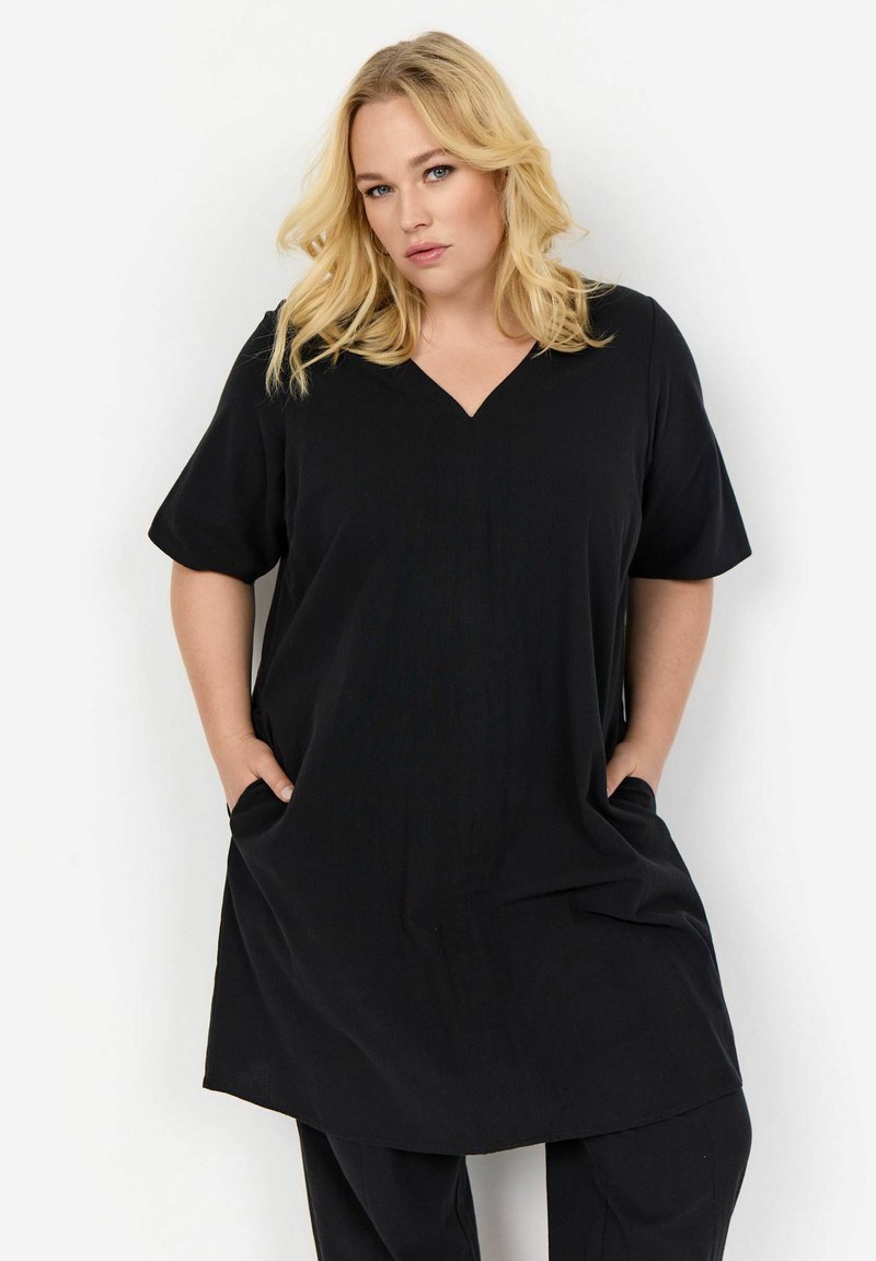 Tunic nera con scollo a V e maniche corte, caratterizzata da una vestibilità ampia e tasche laterali, realizzata in tessuto morbido e leggero.