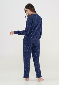 Conjunto de pijama azul marino que incluye una camiseta de manga larga y pantalones, fabricado en tejido suave, decorado con pequeñas estrellas blancas y rosas.