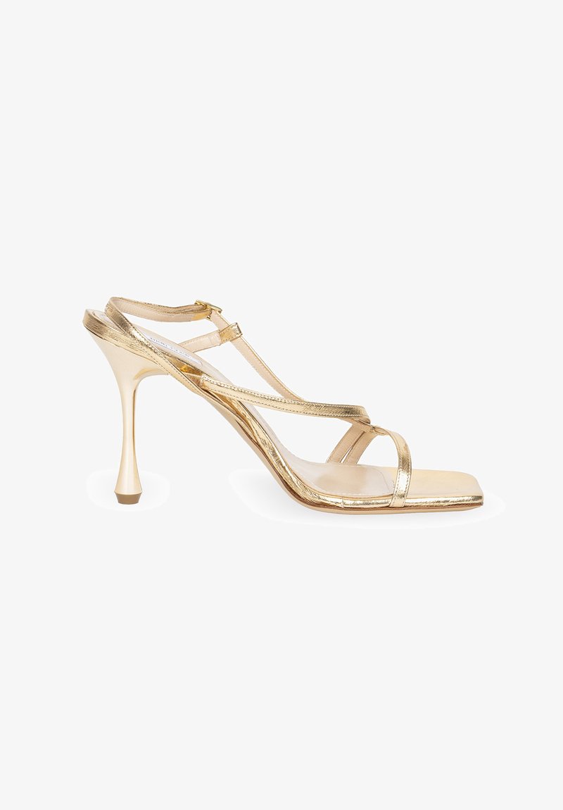 Złote metaliczne sandały na wysokim obcasie o eleganckim designie, z cienkimi paskami, kwadratowym noskiem i unikalnym zwężającym się obcasem zapewniającym stabilność.
