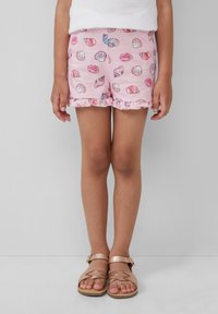 Shorts roses avec un motif de coquillages, dotés d'un ourlet volanté. Associés à des sandales marron clair, mettant en valeur un design de lanière.