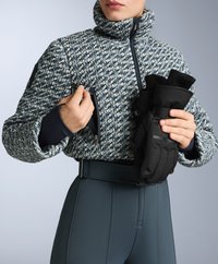 Jakna s teksturama u plavo-bijelom uzorku sa visokim ovratnikom i zip džepovima; model drži crne rukavice; uske, tamno sive hlače s remenom.