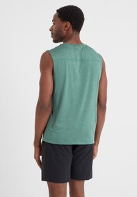 Green, sleeveless athletic top made of textured material. Features a back yoke and relaxed fit, paired with black shorts.