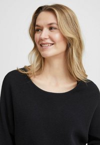 Schwarzer gerippter Pullover, weiter Rundhalsausschnitt, lange Ärmel. Weicher Stoff mit lockerer Passform, geeignet für die Freizeit.