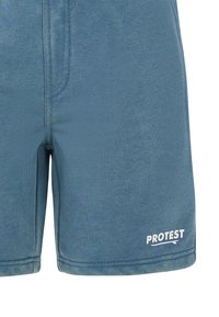 Modré šortky vyrobené z měkkého materiálu, s hladkou texturou, elastickým pasem a bílým logem na dolním pravém boku.