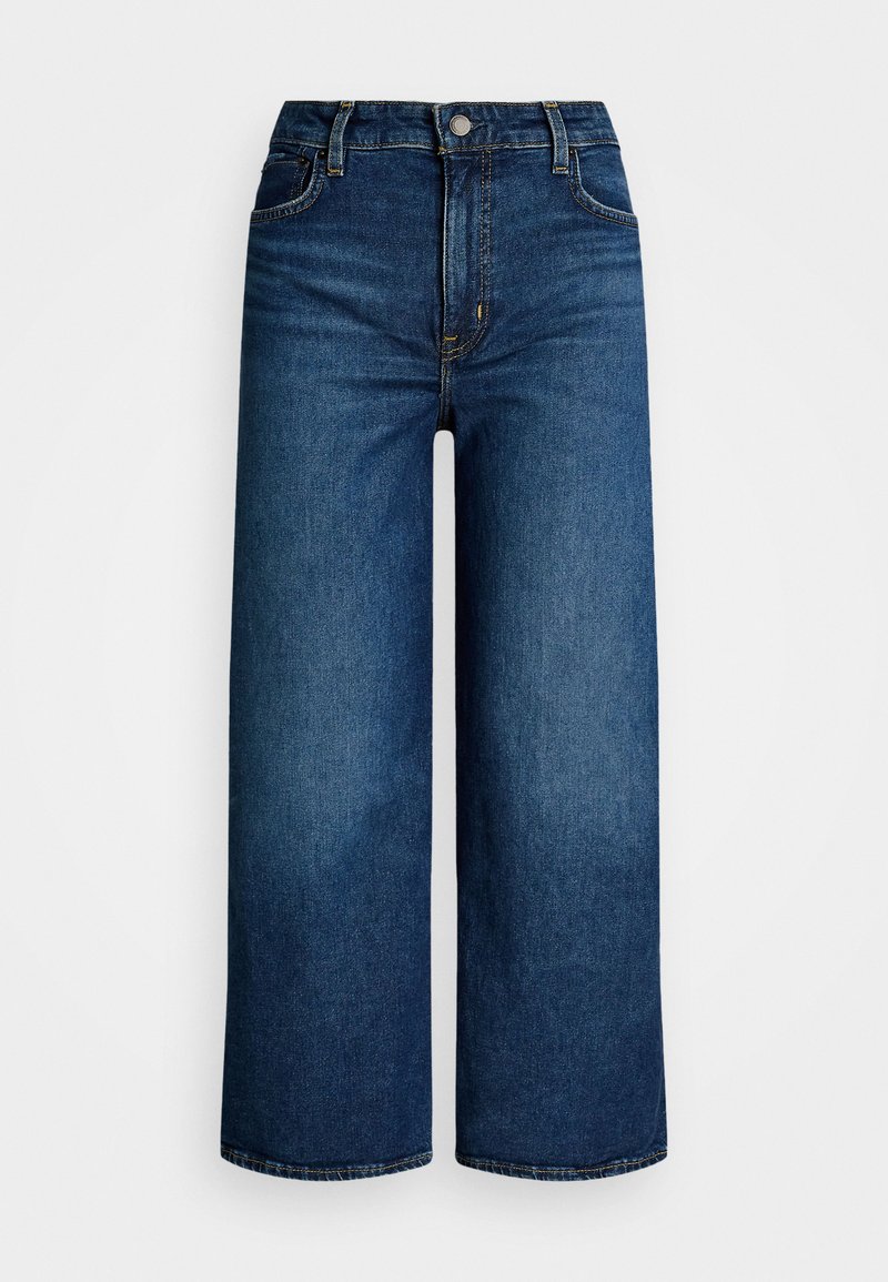 Jeans z wysokim stanem i szerokimi nogawkami, wykonane z ciemnoniebieskiego denimu o gładkiej fakturze, z widocznymi szwami i kieszeniami z przodu.