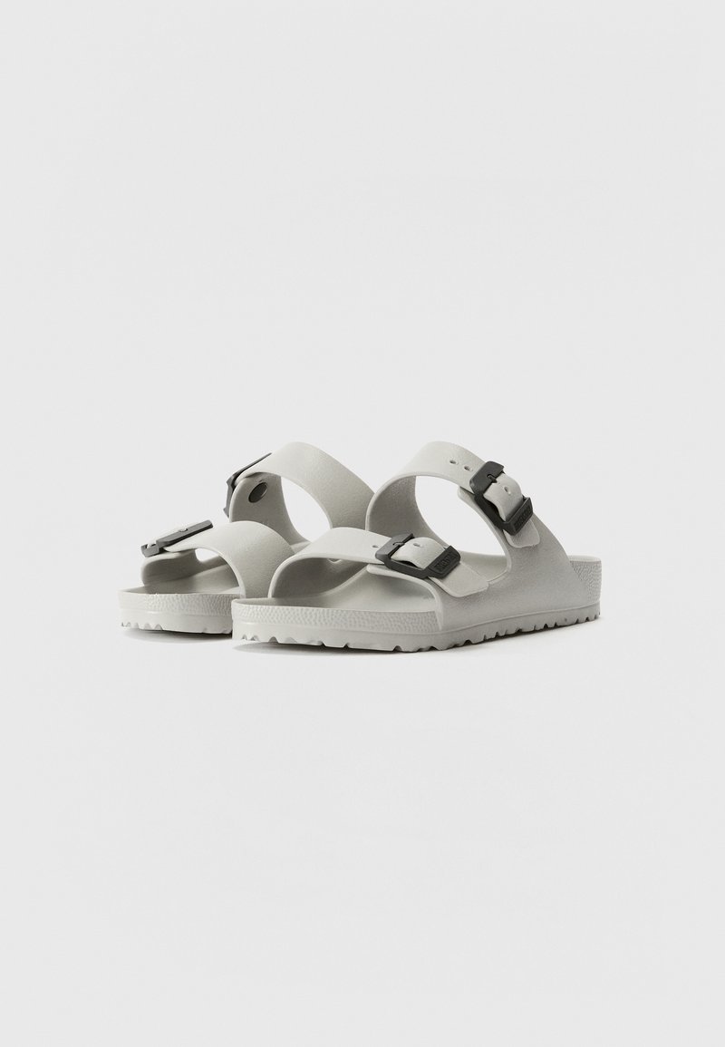 Hellgraue Sandalen mit einem breiten Riemendesign, zwei verstellbaren schwarzen Schnallen, strukturiertem Fußbett und einer Gummisohle mit Profil.