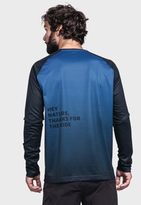 Langarmhemd in einem Verlauf von Blau und Schwarz, aus strukturiertem Stoff mit einem gedruckten Spruch auf der Rückseite: "HEY NATUR, DANKE FÜR DIE FAHRT."