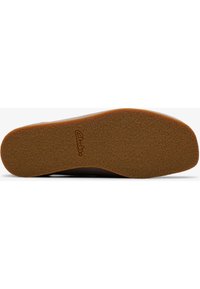 Semelle de chaussure en caoutchouc marron présentant une surface texturée, une forme arrondie, avec une semelle extérieure marron clair et un détail de logo en relief.