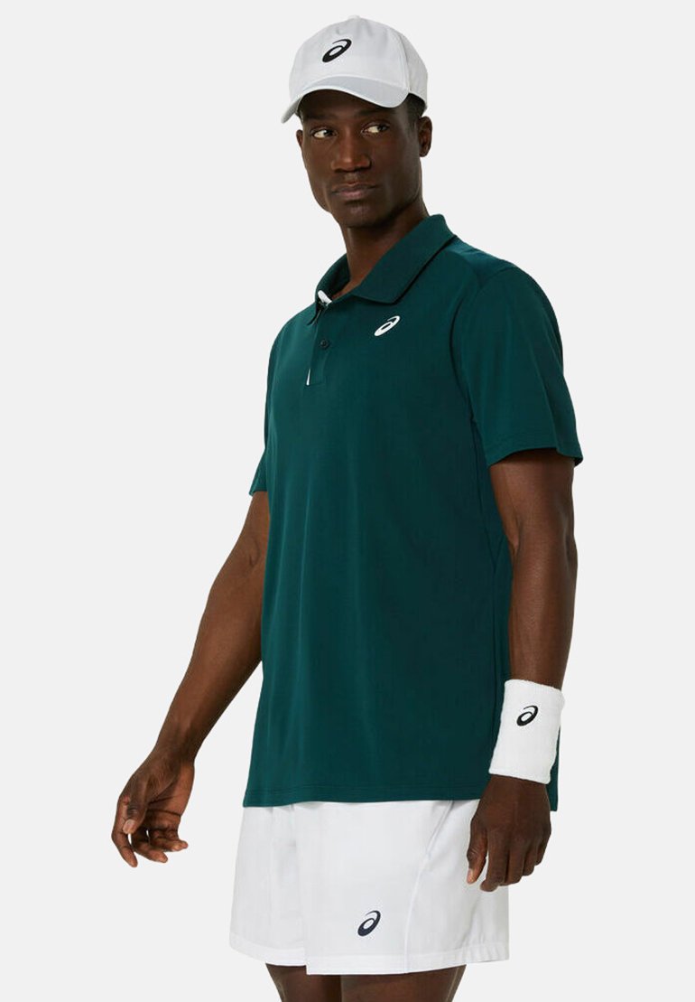 Polo shirt teal con colletto a bottoni, abbinato a pantaloni corti bianchi e un braccialetto. Un cappellino bianco presenta un logo sulla parte anteriore.