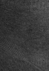 Schwarze gerippte Baumwollsocke mit glatter Textur und gleichmäßigem Webmuster. Keine sichtbare Markenkennzeichnung oder Muster, entworfen für Komfort.